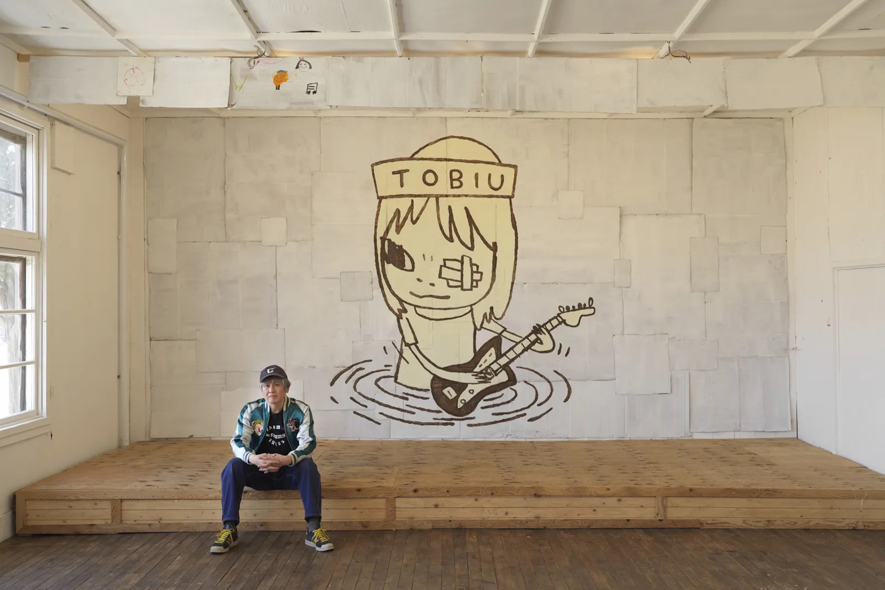 Yoshitomo Nara seated in front of TOBIU, 2019, donated by the artist to the TWO x TWO for AIDS and Art auction, 2021 | Source: Yoshitomo Nara Foundation